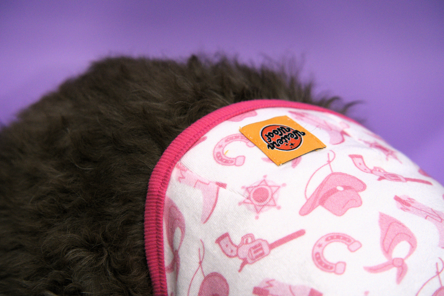 Close-up of a dog shirt with pink cowboy themed pattern