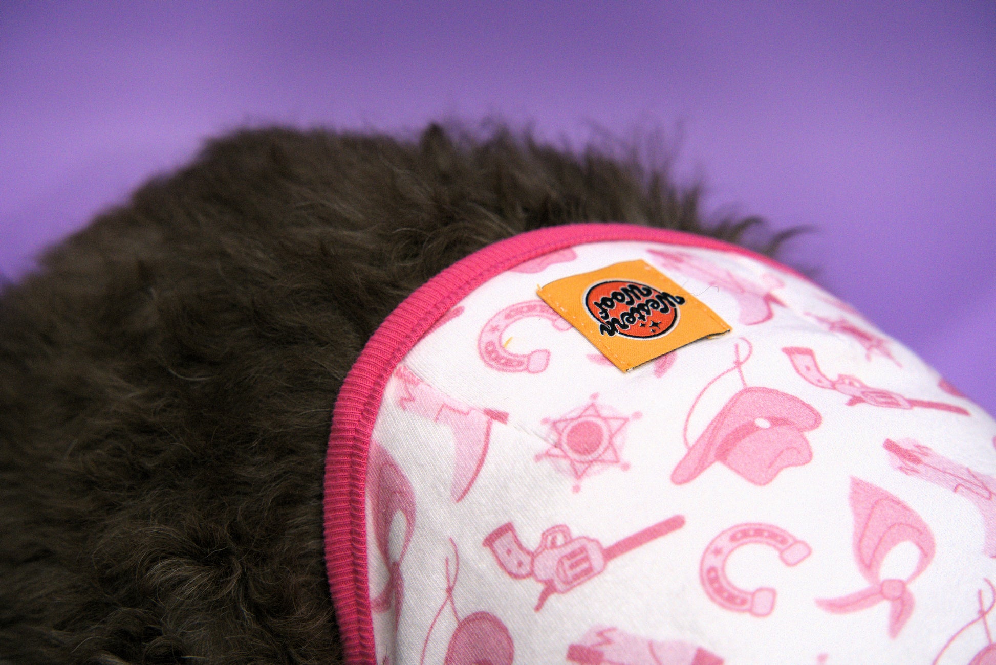 Close-up of a dog shirt with pink cowboy themed pattern
